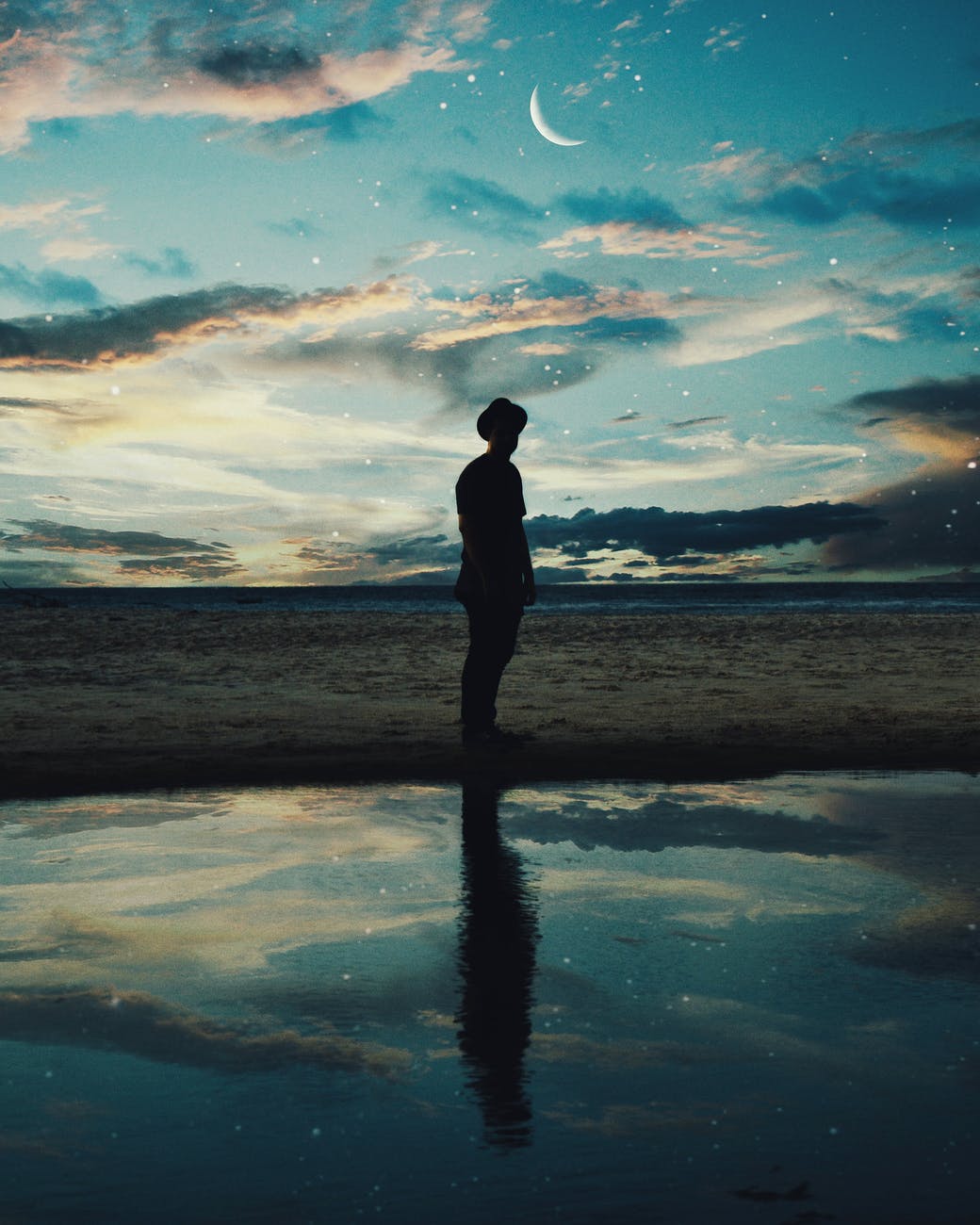 silhouette of man standing near body of water